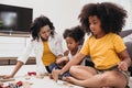 Single mom with two daughter playing toy in apartment. Nanny looking or childcare at home black people