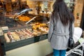 Single mother admiring French sweet pastry in bakery window