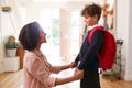Single Mother At Home Getting Son Wearing Uniform Ready For First Day Of School