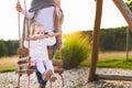 Single mother with toddler daughter swinging on a playground. Childhood, Family, Happy, Summer Outdoor Concept Royalty Free Stock Photo