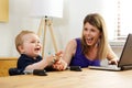 Single mother working on laptop with her baby boy at home Royalty Free Stock Photo