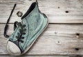 Single old blue worn out running shoe on wood background.