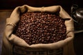 Single open burlap satchel on side with whole coffee beans spilling out over wood panel Royalty Free Stock Photo