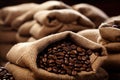 Single open burlap satchel on side with whole coffee beans spilling out over wood panel Royalty Free Stock Photo