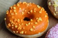 single orange donut with sprinkles on a wooden background Royalty Free Stock Photo