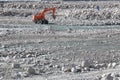 Single orange excavator in vast landscape