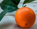 Single orange fruit with leaves on the wooden table