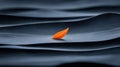 A single orange leaf floats on a dark blue wave. Royalty Free Stock Photo