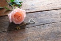 Single orange-pink rose and heart key shape on vintage wooden floor under soft warm light. Backdrop for Valentine& x27;s day. Love Royalty Free Stock Photo