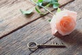 Single orange-pink rose and Love key shape on vintage wooden floor under soft warm light. Backdrop for Valentine's day Royalty Free Stock Photo