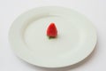 Single organic and fresh strawberry on a white plate. Royalty Free Stock Photo