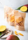 Single packages with various sweet dried mango pieces with fresh fruits