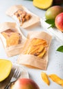 Single packages with various sweet dried mango pieces with fresh fruits