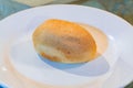 Single pandesal bread roll on white plate in minimalist dining setting Royalty Free Stock Photo