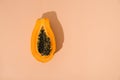 single papaya fruit cutter on half on pastel background