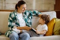 Single Parent. Young Mom And Her Toddler Daughter Reading Book At Home, Royalty Free Stock Photo
