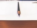 Single pencil on a white table with wooden side panel