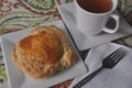 Single person breakfast of sweet pastry with fruit jam and a cup of hot tea on a colorful background