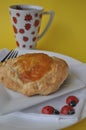 Single person breakfast of sweet pastry with fruit jam and a cup of hot tea on a colorful background