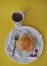 Single person breakfast of sweet pastry with fruit jam and a cup of hot tea on a colorful background