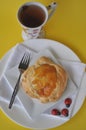 Single person breakfast of sweet pastry with fruit jam and a cup of hot tea on a colorful background