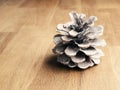 A single pine cone on a rustic wooden table with space for text