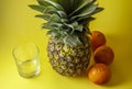 Single pineapple isolated on yellow background with empty glass Royalty Free Stock Photo