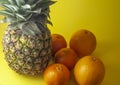 Single pineapple isolated on yellow background with oranges and Royalty Free Stock Photo