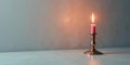 A single pink candle flame illuminates a metallic candlestick on a light surface against a textured backdrop. Generative AI Royalty Free Stock Photo