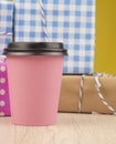 Single pink paper cup of coffee and heap gift boxes