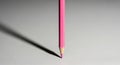 A single pink pencil casting a long dramatic shadow on a textured surface Royalty Free Stock Photo