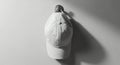 Minimalist Black and White Image of a Plain Baseball Cap Hanging on a Wall Hook Royalty Free Stock Photo