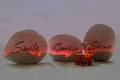 Single positive on three fire red stones - smile sparkle and shine. With smiling paper clip on white table background. Self love.