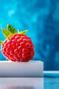 A single raspberry sitting on top of a white block Royalty Free Stock Photo