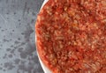 Single raw hamburger patty on a white plate top close view atop a gray mottled background