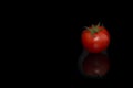 Single real tomatoe seen at its top on a black background with reflection