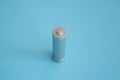 A single rechargeable battery on blue background. Silver alkaline AA battery for different device. Energy.