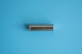 A single rechargeable battery on blue background. Silver alkaline AA battery for different device. Energy. Royalty Free Stock Photo