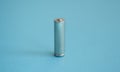 A single rechargeable battery on blue background. Silver alkaline AA battery for different device. Energy.