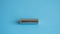 A single rechargeable battery on blue background. Silver alkaline AA battery for different device. Energy. Royalty Free Stock Photo
