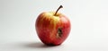 Single red apple with yellow stripes shows decay damage on its side. Fruit rests isolated on a plain white backdrop with soft Royalty Free Stock Photo