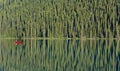 A single red canoe floats on a glassy Lake Louise