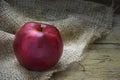 Single red christmas apple on rough bag fabric and rustic wood Royalty Free Stock Photo