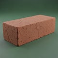 A single red clay brick with cracks on a green background, showing texture and details Royalty Free Stock Photo