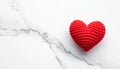 One red crocheted heart on a white marble surface with grey veining love knitted Royalty Free Stock Photo