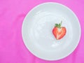 single red heart the strawberry sweet fruit a closeup texture of red berry heart-shaped fruits by half cut in white plate on pink Royalty Free Stock Photo