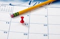 Single red pushpin on April 15 of calendar for tax income due date reminder on desktop with pencil