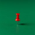 A single red pushpin with a plastic head and metallic needle stands upright against a Royalty Free Stock Photo