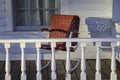 A single red retro-style metal rocking chair sits on a wooden porch. Royalty Free Stock Photo