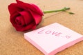 Single red rose with post it with word